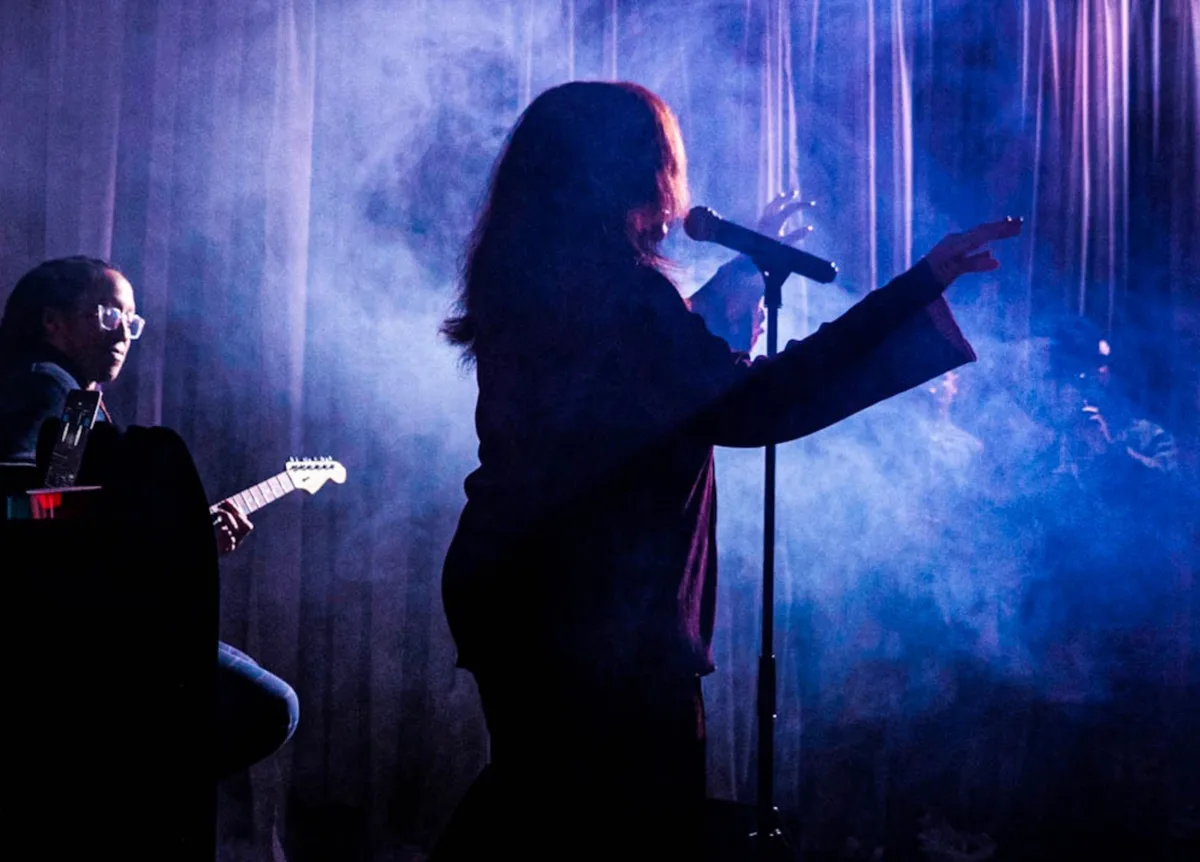 Event consulting with performer on stage under dramatic blue lighting