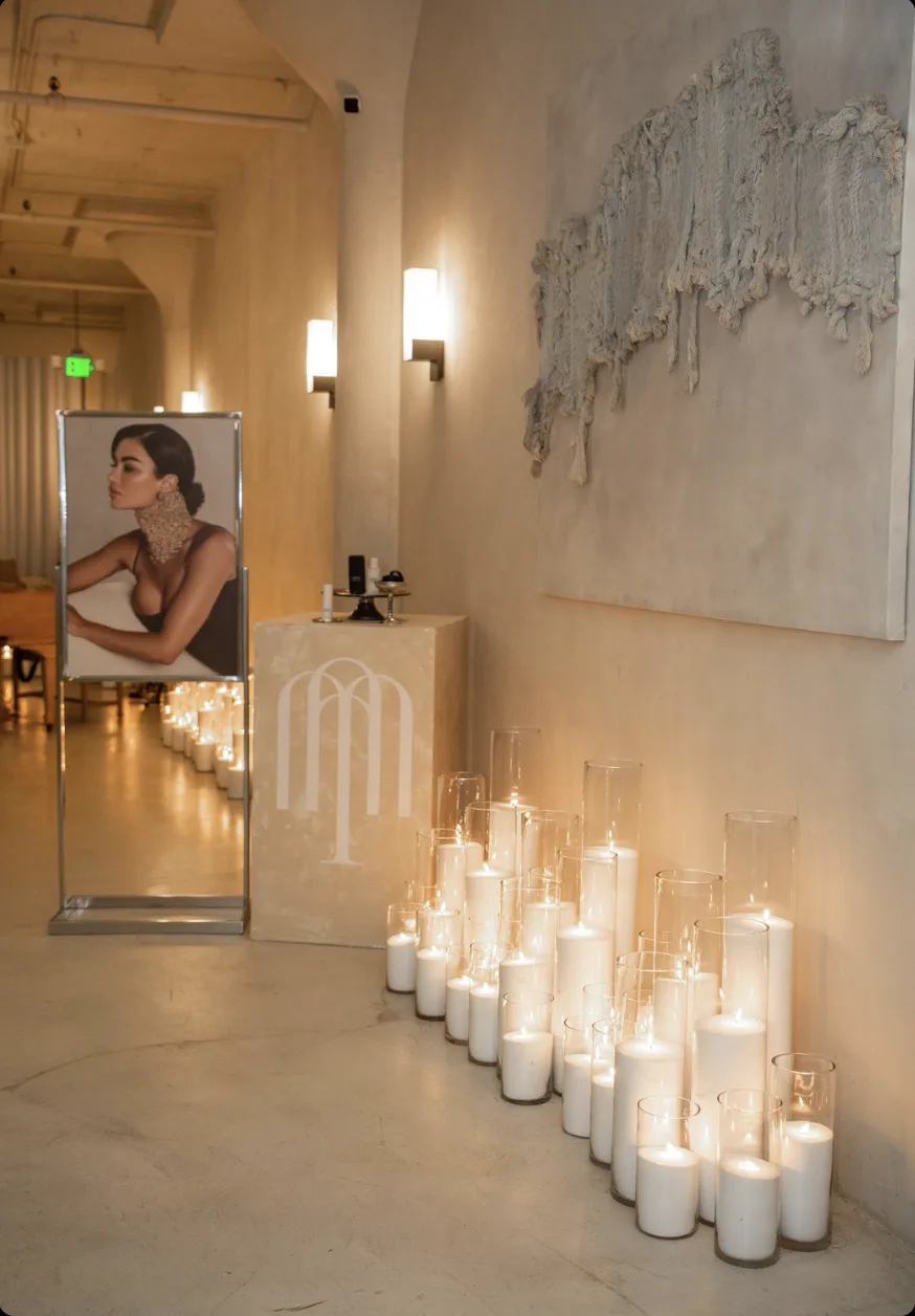 Entry vignette with portrait, branded plinth and floor candle cluster