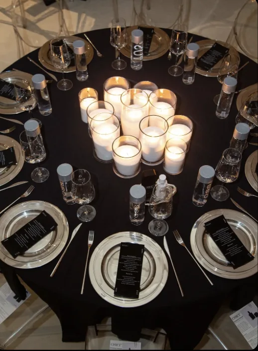 Round table with black linens, branded menus and pillar candles